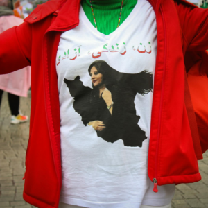 Close-up of a person wearing a red jacket and printed T-shirt outdoors, featuring artistic calligraphy.