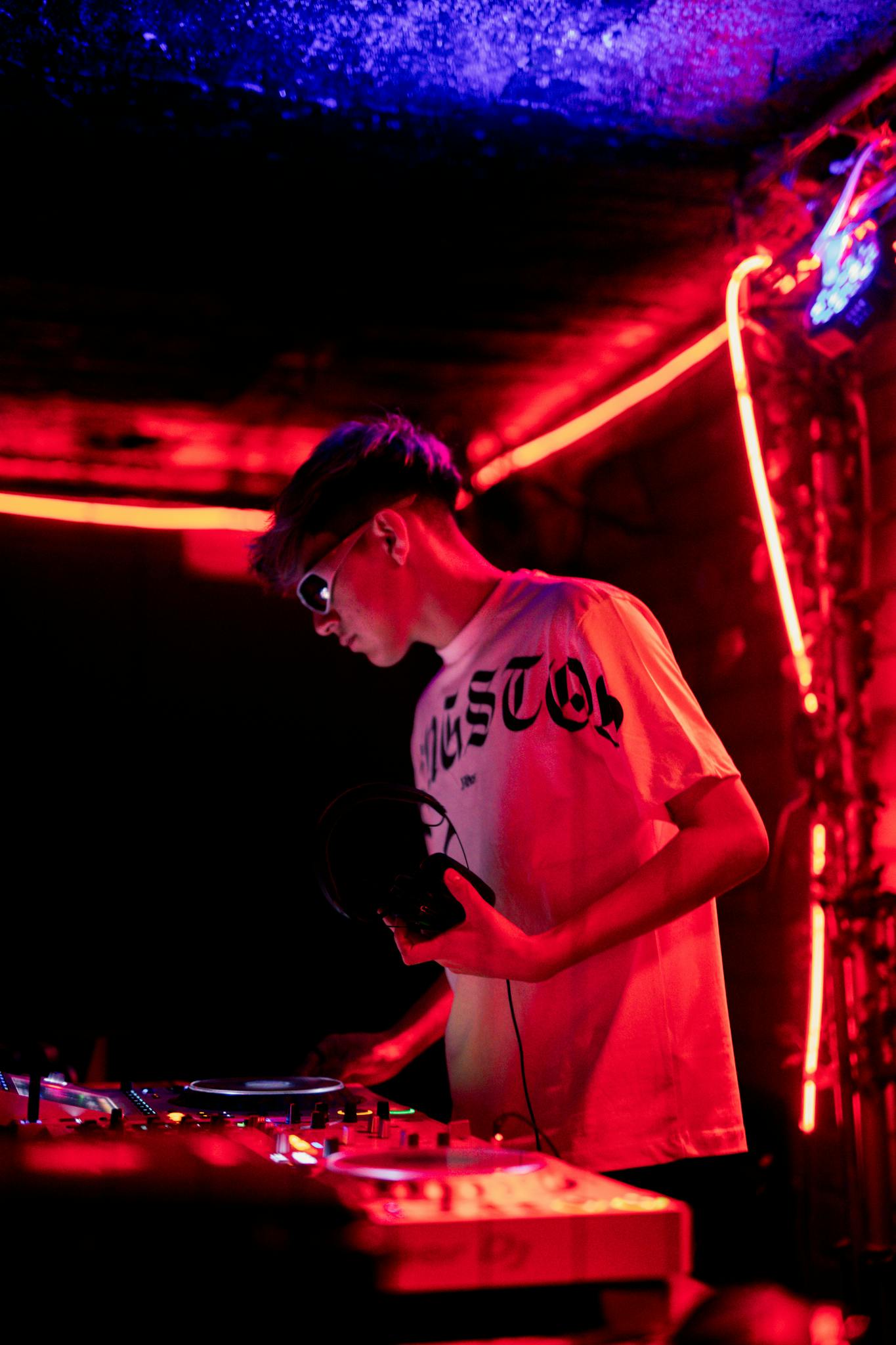 DJ focusing on music mixing in a vibrant neon nightclub.