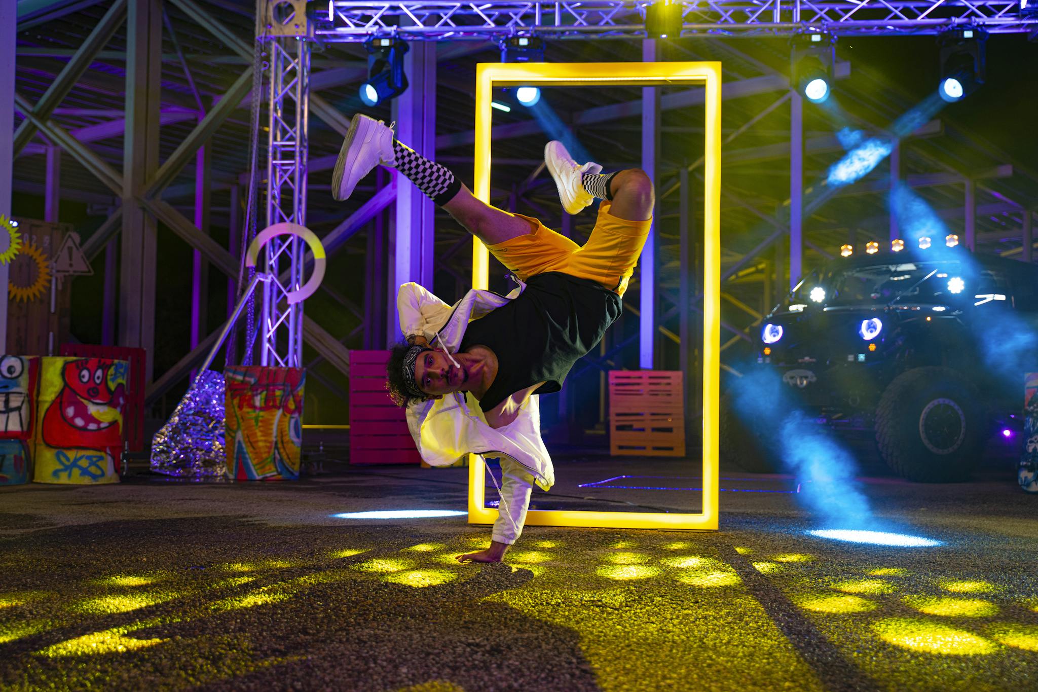 Energetic breakdance with vibrant neon lights and colorful artwork backdrop.